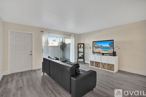 A living room with a grey sofa and a television on a white cabinet.