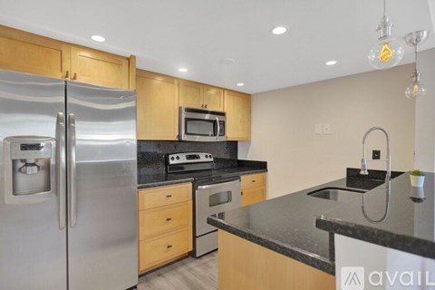A kitchen with a stainless steel refrigerator and wooden cabinets.