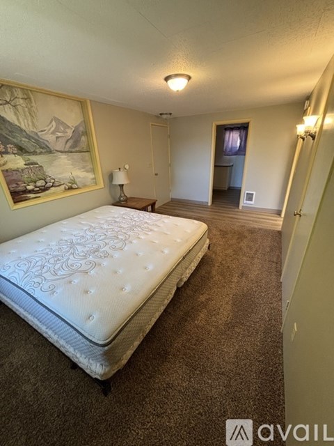 A bedroom with a large bed and a painting on the wall.