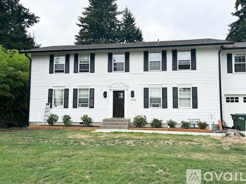 A white house with a black door and windows is for sale.