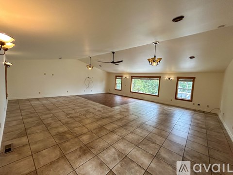 A spacious room with tiled flooring and a chandelier.