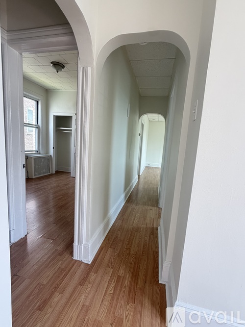 A long hallway with arched doorways and wood floors.