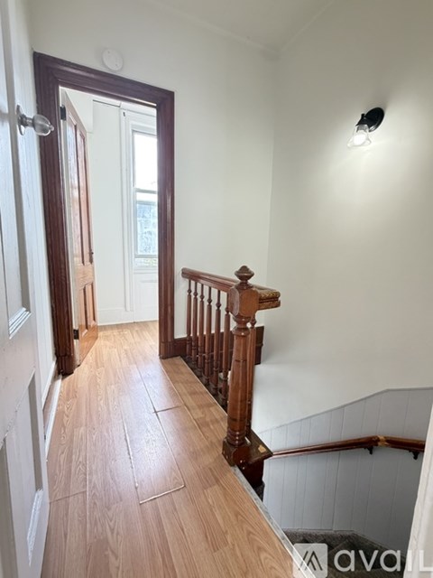 A hallway with wooden floors and a staircase.