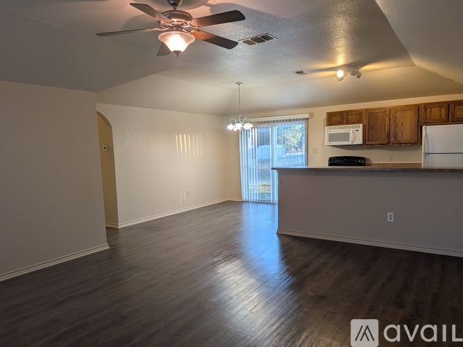 A spacious kitchen and living room with wood flooring and a ceiling fan.
