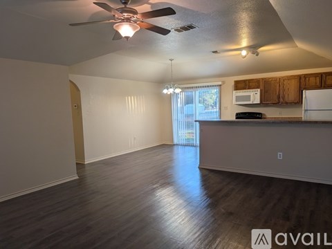 A spacious kitchen and living room with wood flooring and a ceiling fan.