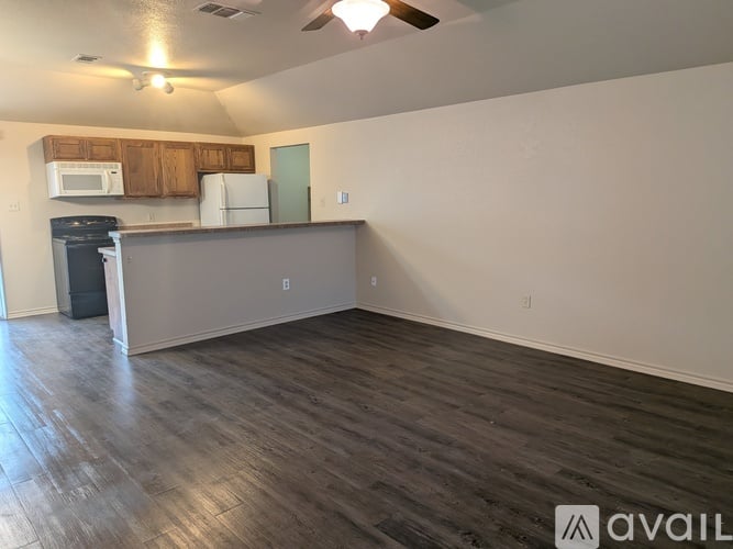 A kitchen area with a refrigerator, microwave, and a trash can.