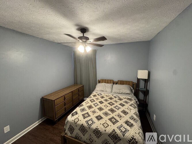 A bedroom with a bed, nightstand, and a ceiling fan.