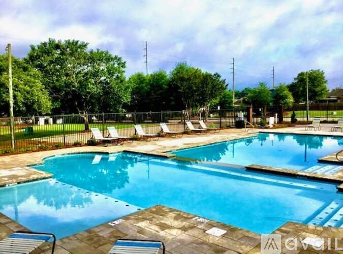 A large outdoor swimming pool surrounded by trees and lounge chairs.