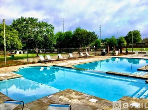 A large outdoor swimming pool surrounded by trees and lounge chairs.