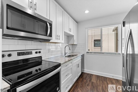 A modern kitchen with white cabinets and stainless steel appliances.