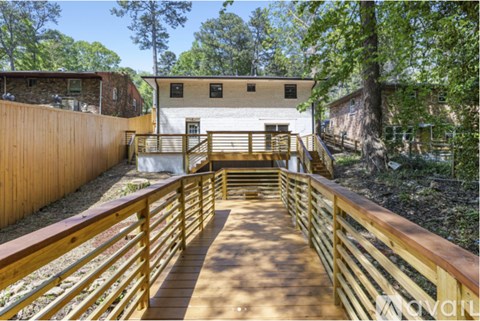 A wooden deck leads to a white building with a brown fence on the left.