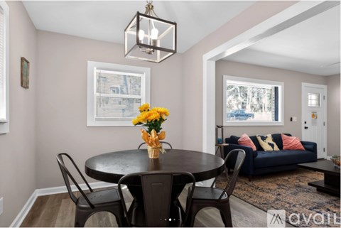 A dining room with a table set for two and a couch in the background.