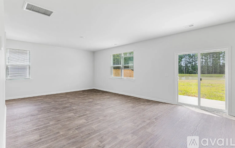 A room with wooden flooring and a sliding glass door leading to a grassy area.