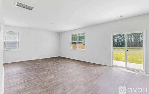 A room with wooden flooring and a sliding glass door leading to a grassy area.