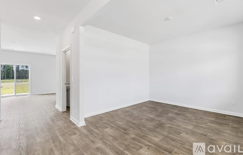 A spacious room with wooden flooring and white walls.