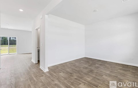 A spacious room with wooden flooring and white walls.