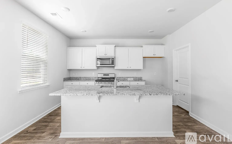 A kitchen with white cabinets and a granite countertop.