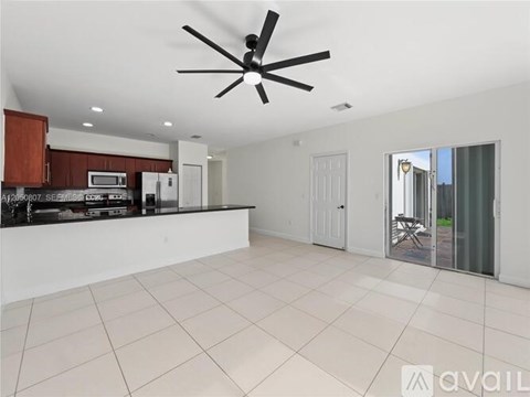 A spacious kitchen with a ceiling fan and a dining area with a table and chairs.