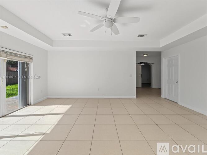 A spacious room with a ceiling fan and tiled flooring.