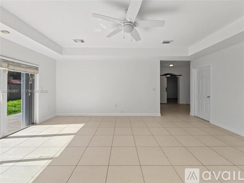 A spacious room with a ceiling fan and tiled flooring.