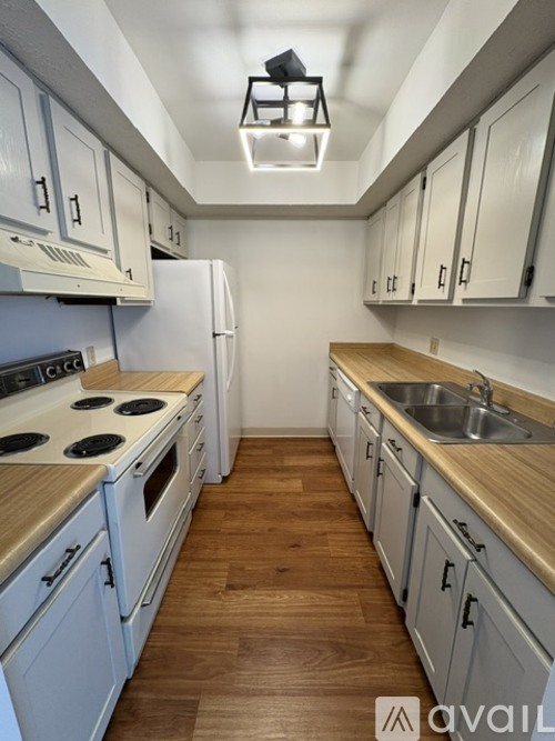 A kitchen with white cabinets and a wooden floor.