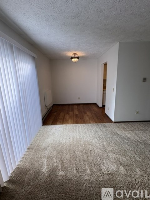 A room with a carpeted floor and a window with blinds.
