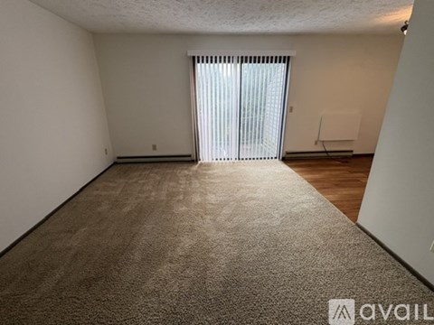 A carpeted room with a window covered by blinds.