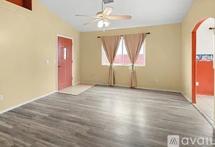 A room with a ceiling fan and a red door.