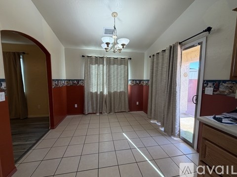 A room with a chandelier, tiled floor, and a window with curtains.