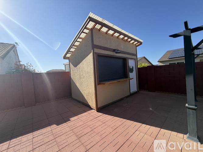 A small building with a window and a door is situated on a patio.
