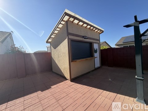 A small building with a window and a door is situated on a patio.