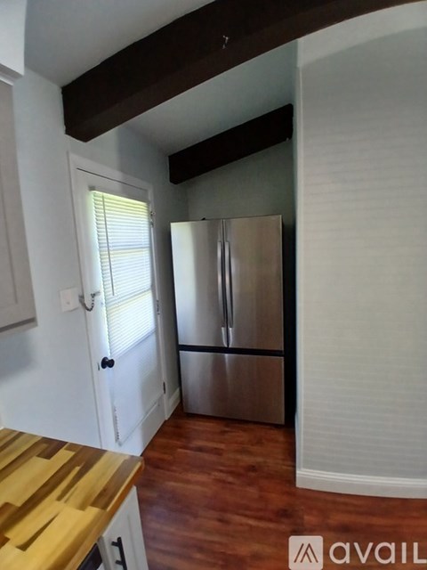 A kitchen with a wooden counter top and a stainless steel refrigerator.