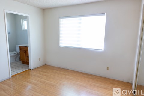 A room with a wooden floor and a window with blinds.