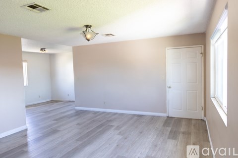 A spacious room with wooden flooring and white walls.