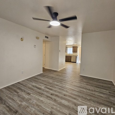 A room with a ceiling fan and wooden flooring.