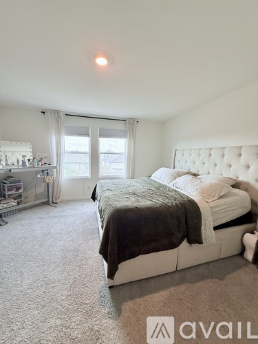 A bedroom with a large bed and a window with curtains.