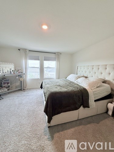 A bedroom with a large bed and a window with curtains.