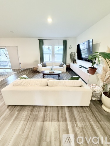 A modern living room with a white sofa and wooden flooring.