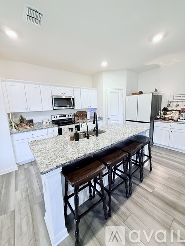 A kitchen with white cabinets and a granite countertop.