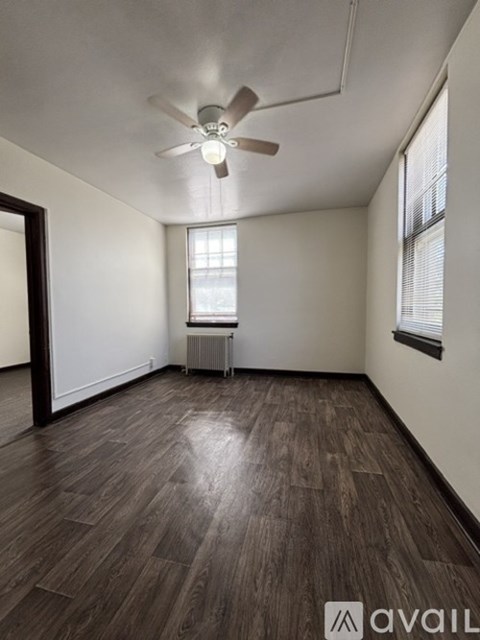 A room with a ceiling fan and wooden flooring.