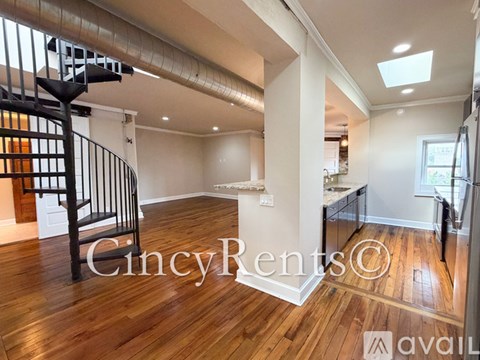 A spacious room with wooden floors and a staircase with a metal railing.