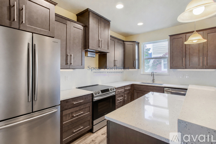 A kitchen with a stainless steel refrigerator and wooden cabinets.