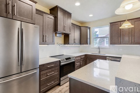 A kitchen with a stainless steel refrigerator and wooden cabinets.