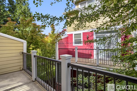 A balcony with a black railing and a view of a red building.