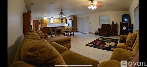 A living room with a row of brown couches facing a television.