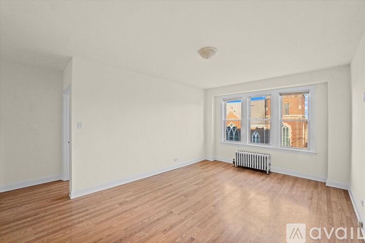 A room with wooden flooring and a window showing a view of buildings outside.