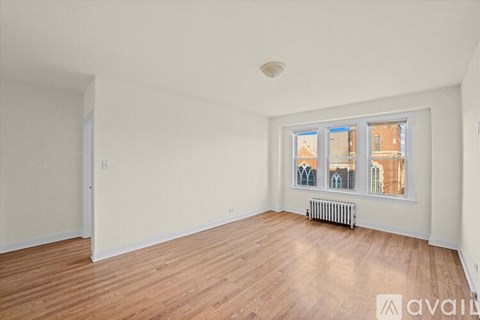 A room with wooden flooring and a window showing a view of buildings outside.
