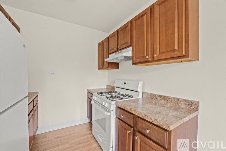 A kitchen with a white stove top oven and wooden cabinets.
