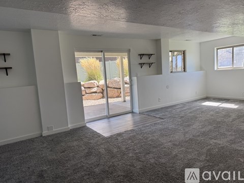 A spacious living room with a carpeted floor and sliding glass doors leading to a backyard.