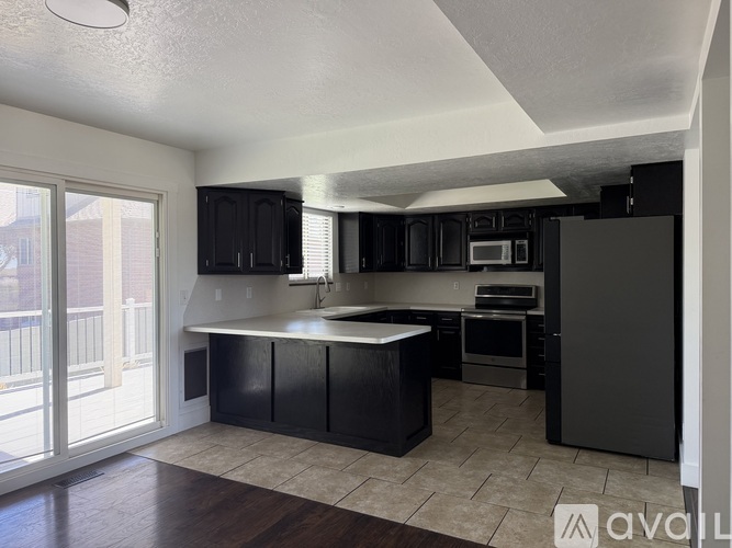 A kitchen with black cabinets and a white island.